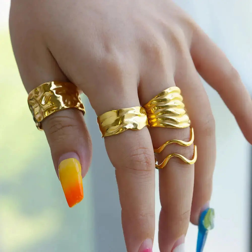 Irregular geometric gold ring displayed on a hand with colorful nails, showcasing its unique and chunky design.